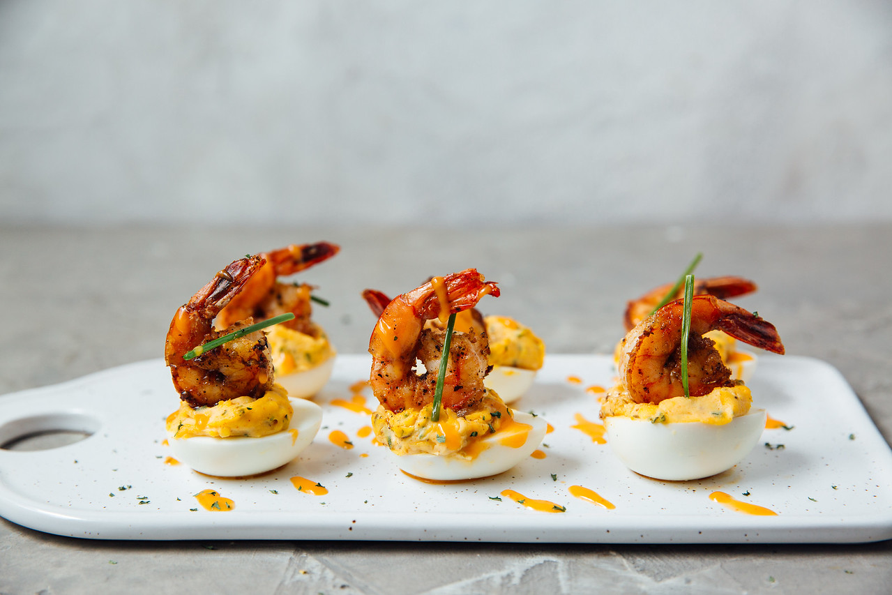 Blackened shrimp-topped deviled eggs arranged on a serving platter