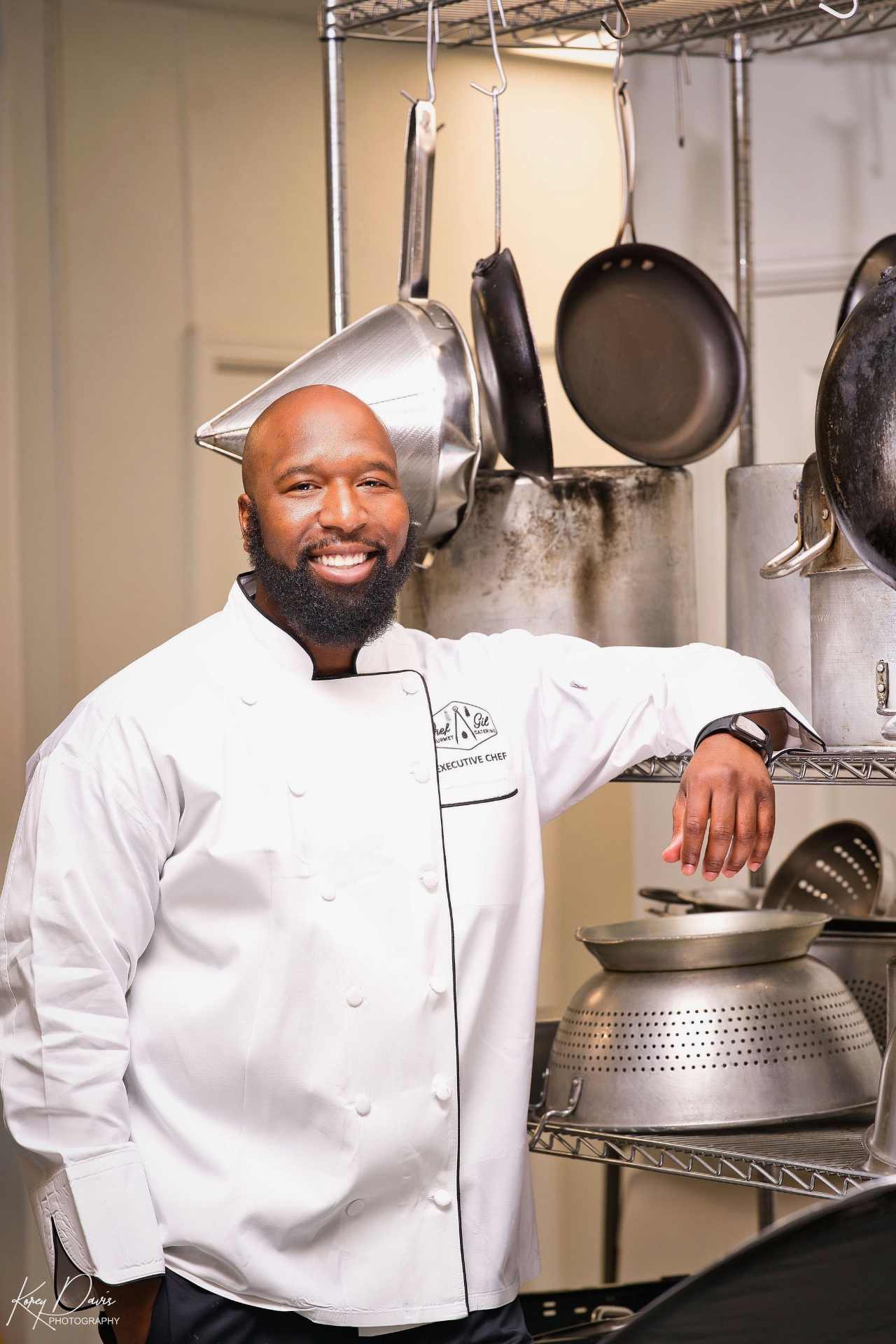 Chef Gilfert Hunt smiling in his white executive chef coat in a professional kitchen