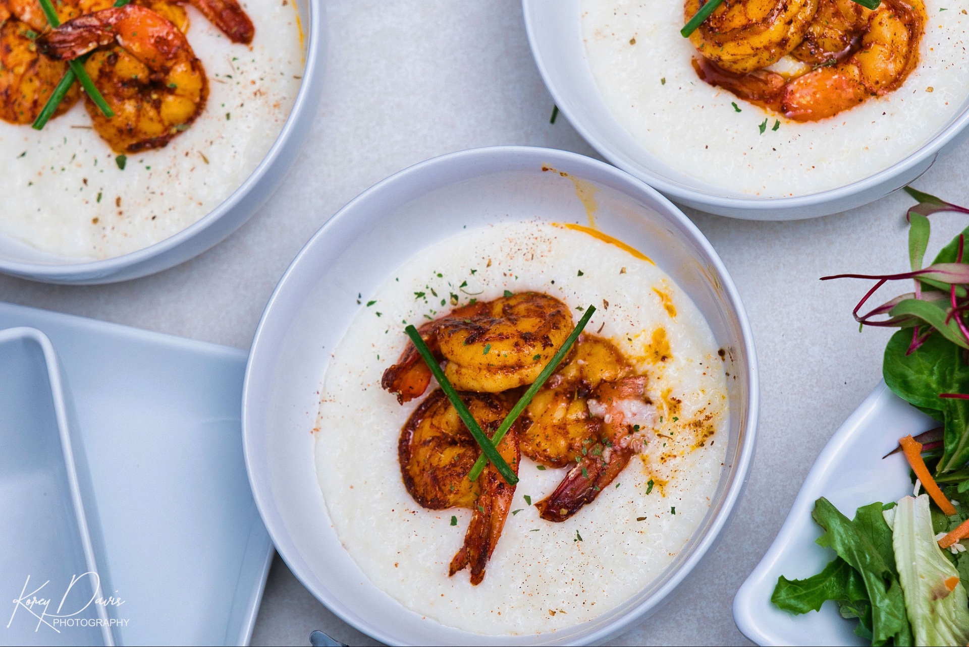 Bowls of blackened shrimp over creamy grits prepared for event service