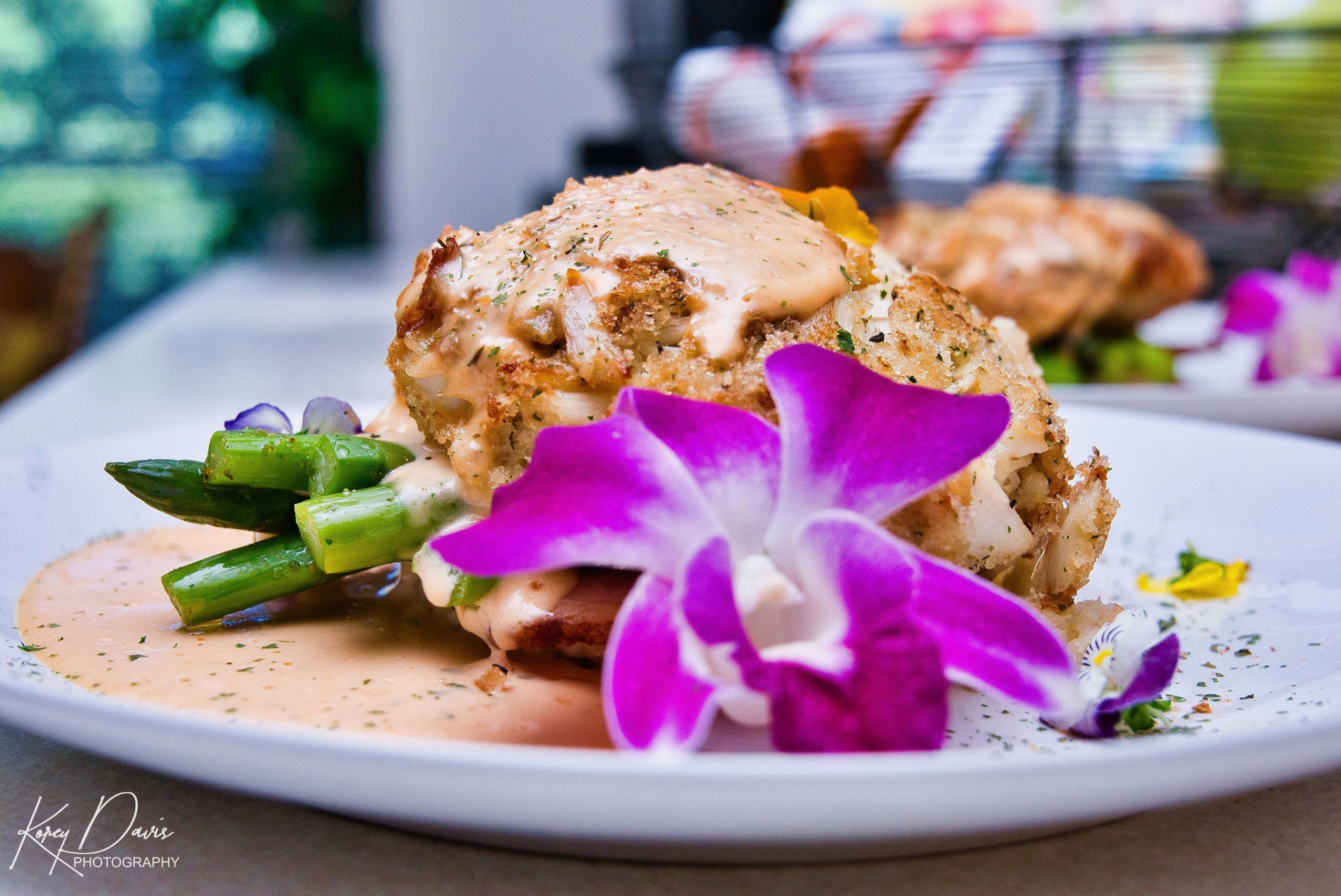 Crab-stuffed seafood entrée with asparagus, sauce, and edible orchid