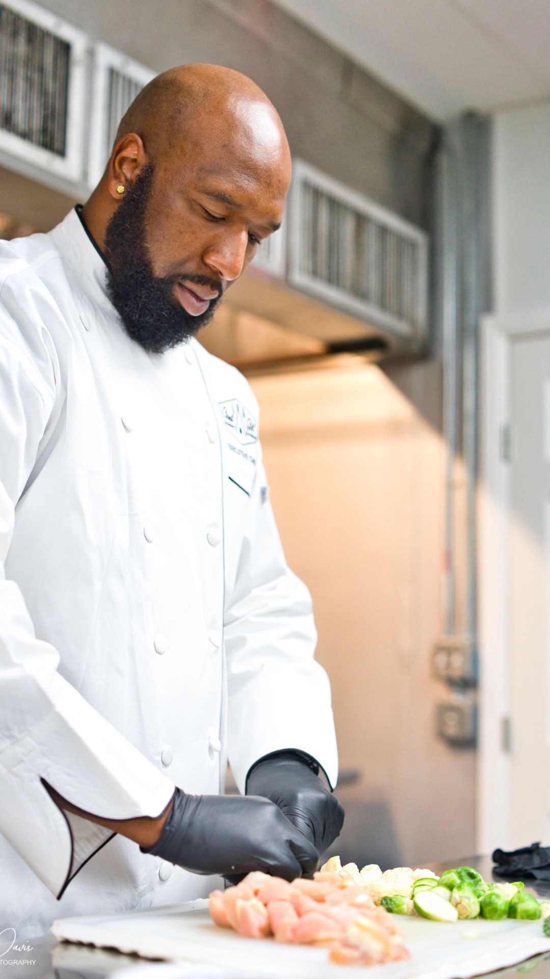 Chef Gilfert Hunt preparing fresh ingredients in his white chef coat